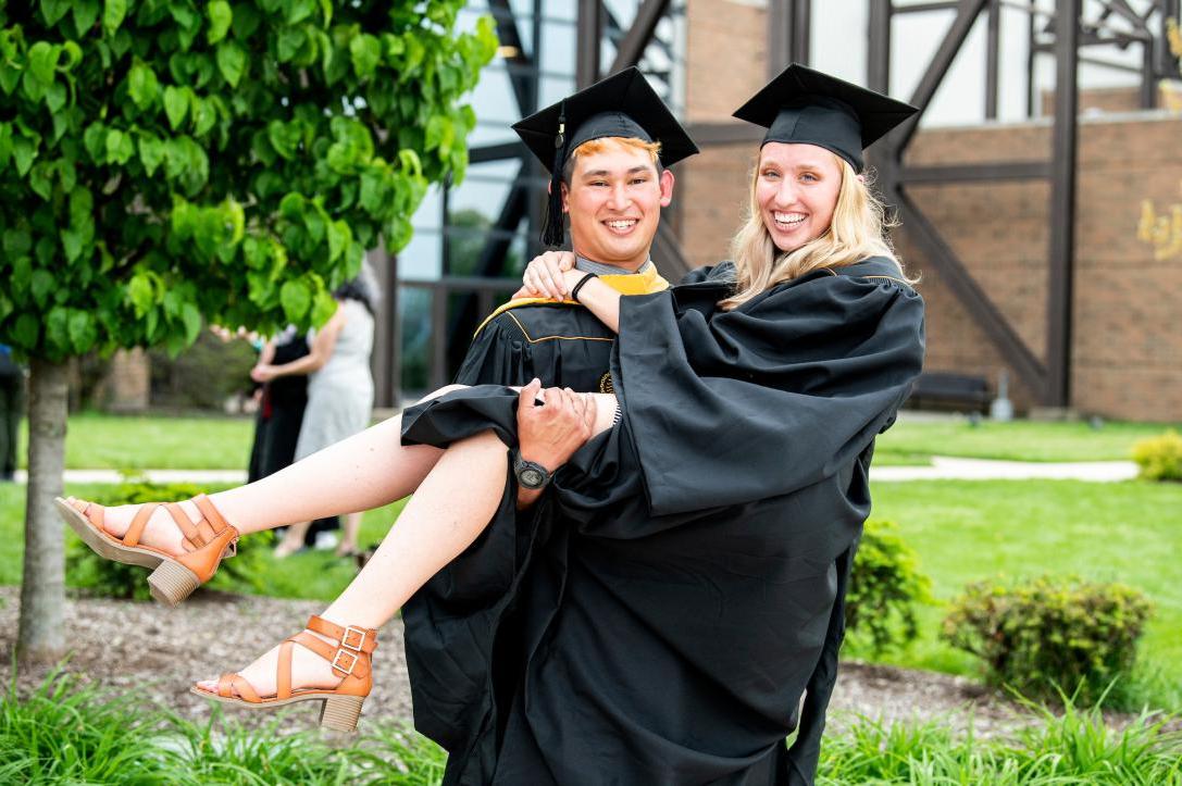 A couple poses for a graduation photo.